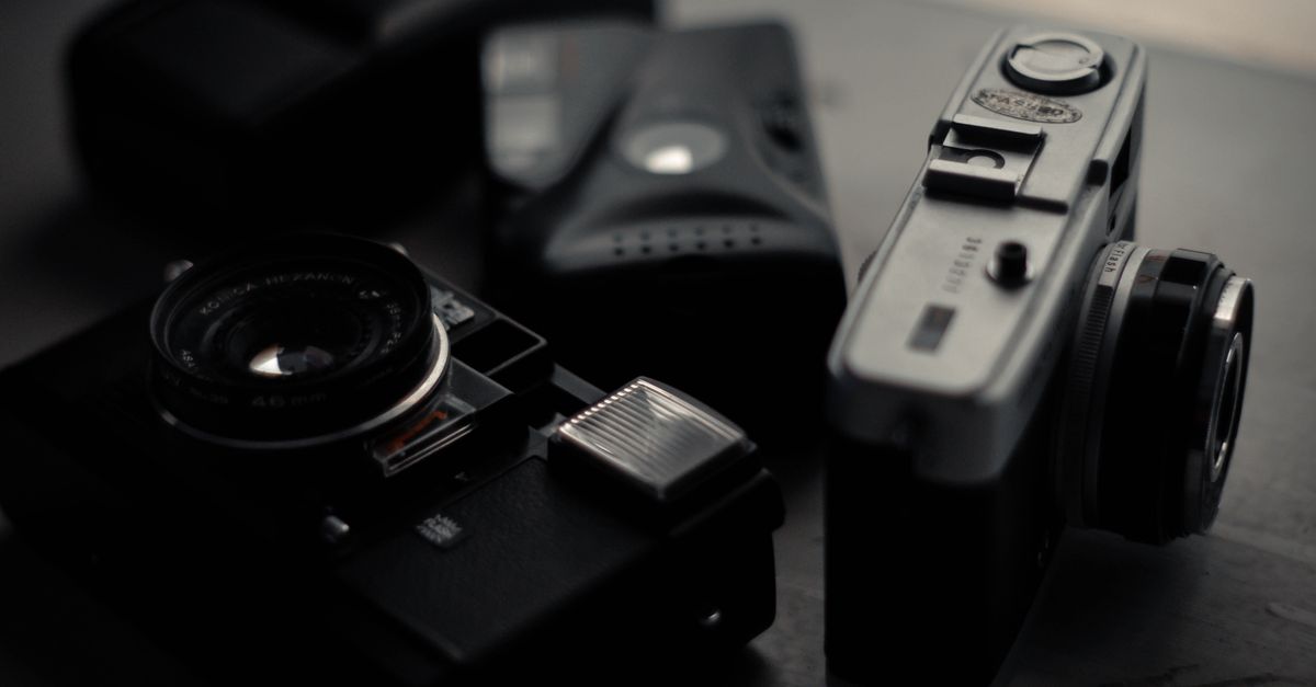 From above of assorted professional retro photo cameras on wooden table in dark room
